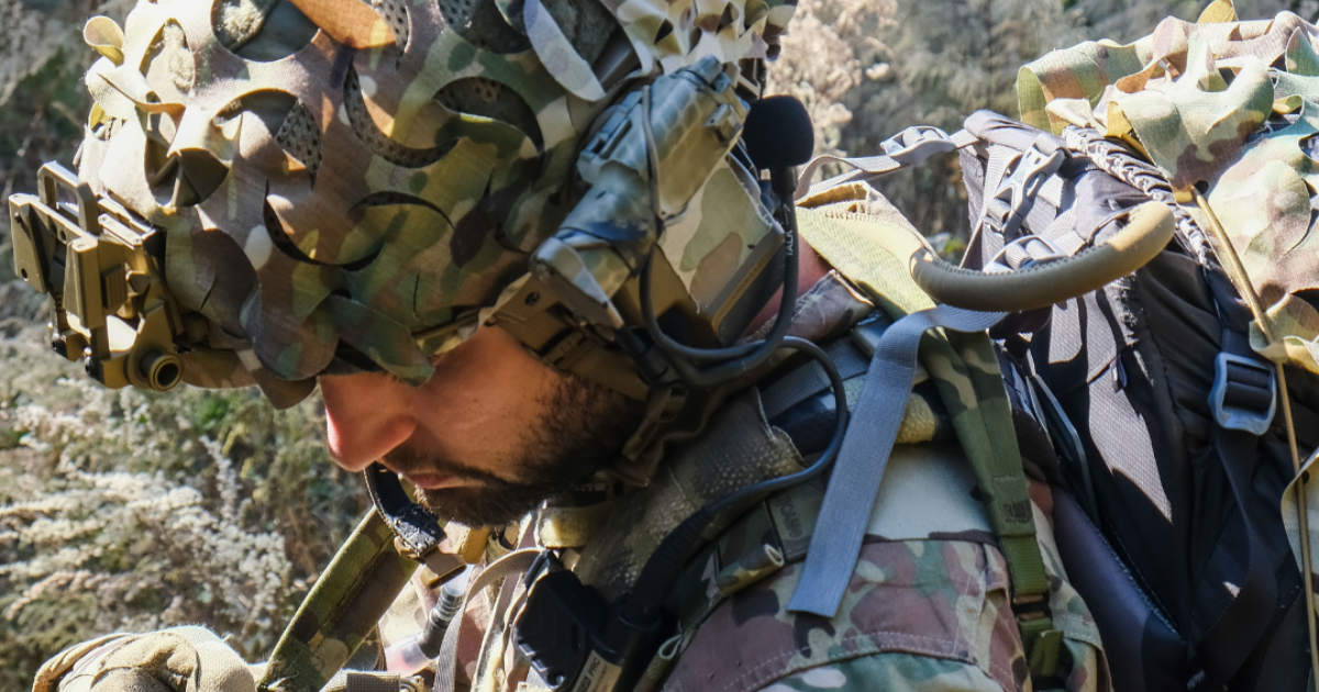 Solider wearing tactical gear and helmet scrim.