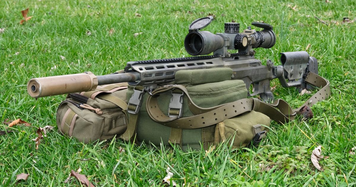 A long range shooting rifle with a rifle sling resting on a shooting bag.