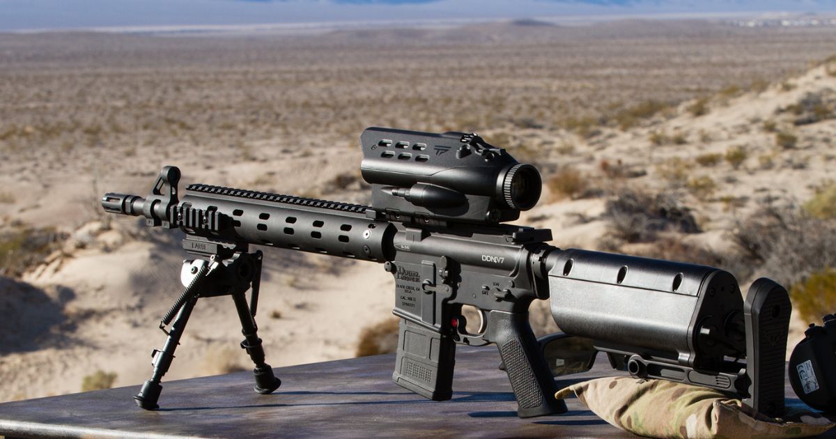 A black rifle on a stand with an optic.