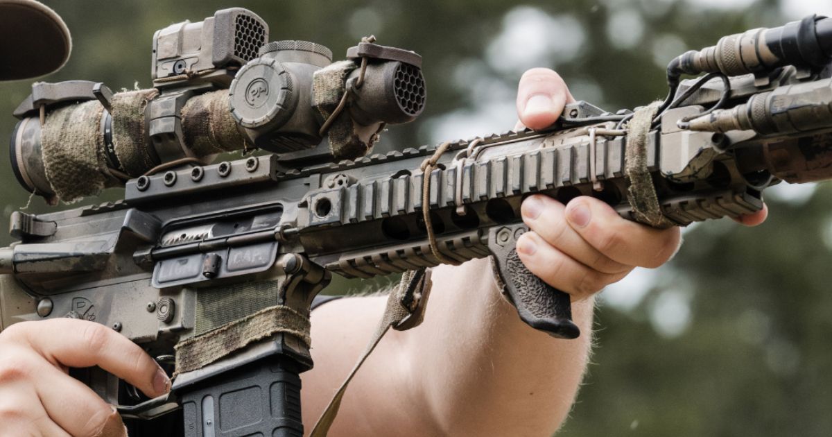 A rifle with a One Hundred Concepts Scope Cap.