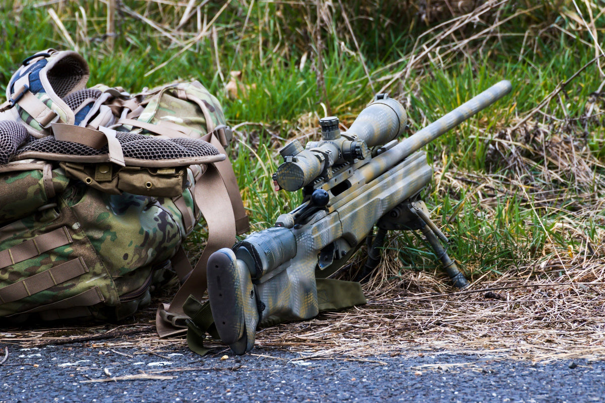 A long distance shooting rilfe next to a gear pack.
